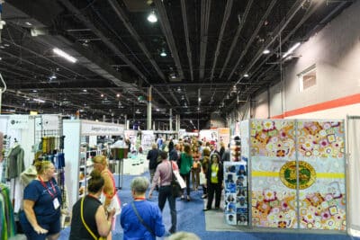 a photo of an exhibit hall showing booths and attendees at h+h americas 2022